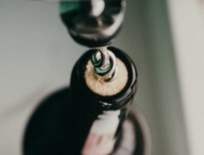 Corkscrew pulling cork from bottle.