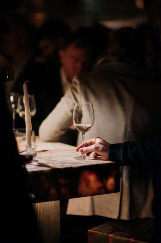 Hand holding wine glass on table.